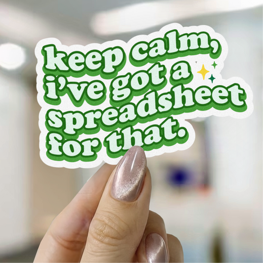 Hand holding a sticker with text 'keep calm, I've got a spreadsheet for that.' against a blurred indoor background.